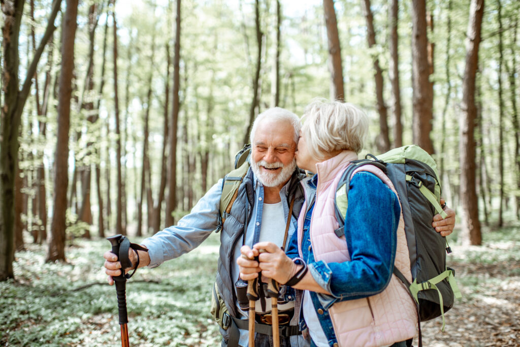 white elderly couple embrace on a hiking trail.