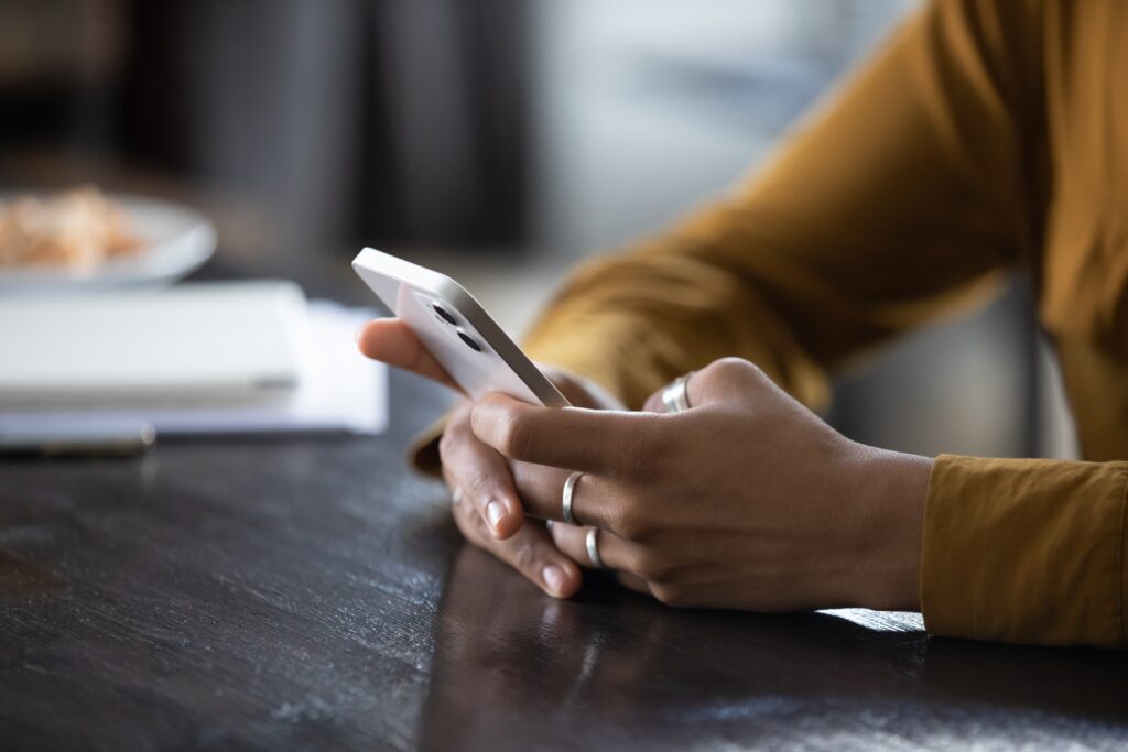 Hands of woman texting on cell while seated at a table