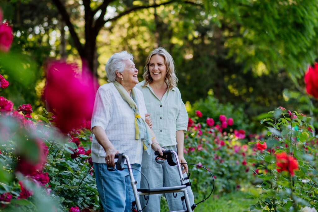 young woman walks with elderly woman in rose garden